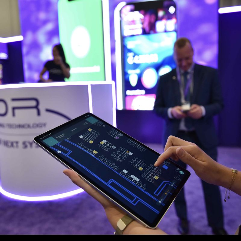 Una persona sostiene una tableta que muestra el plano digital del piso de juego con la distribución de máquinas en tiempo real