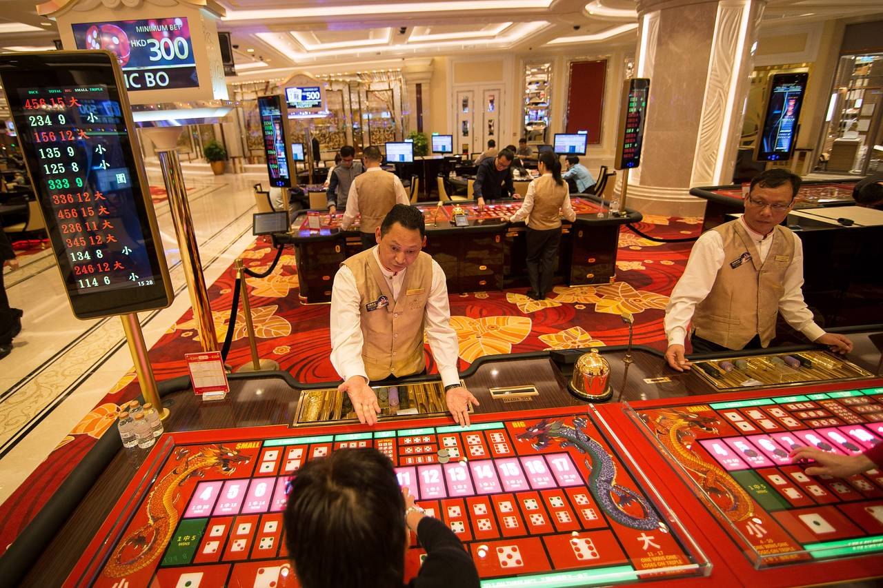 Crupieres atendiendo una mesa electrónica de Sic Bo en un casino de Macao